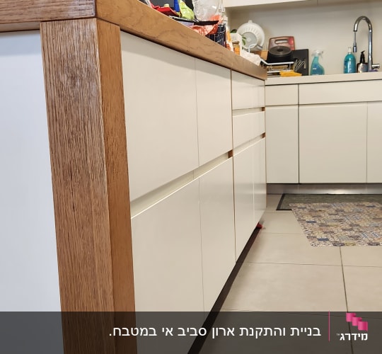 מטבח מודרני עם ארונות לבנים ומשטח עץ